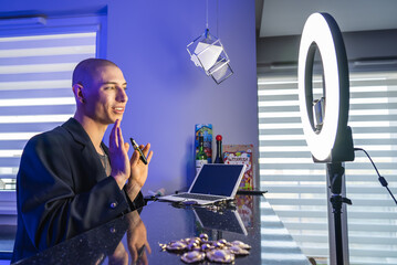 European queer influencer does makeup in the bathroom in front of the mirror using professional...