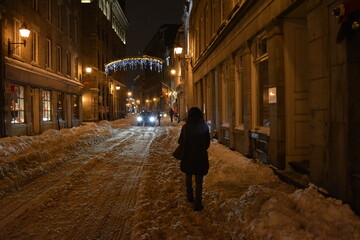 A woman walking down a street at night in Montreal