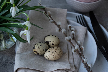 Easter set - plate, fork and knife, quail eggs and snowdrops on the table
