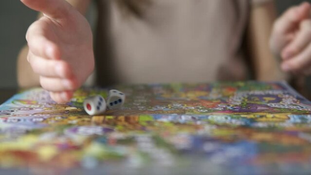 Board game for children. A child move dice on the table with board game.