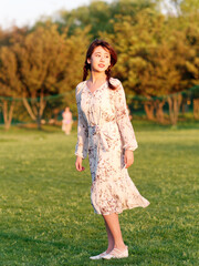 Portrait of elegant Chinese girl in dress enjoy carefree time in forest park in sunny day. Outdoor fashion portrait of glamour young Chinese cheerful stylish woman.
