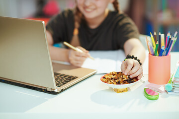 Girl homeschooling and eating healthy snack at home in sunny day