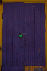 dark purple door to the old house with green padlock
