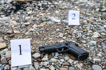 gun on the crime scene evidence on the beach or sand rocks used for murder or shooting with tag...