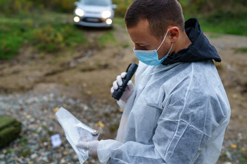 one man forensic police investigator collecting evidence in the plastic bag at the crime scene...