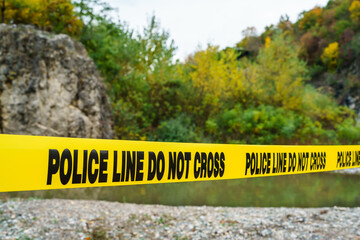 police line do not cross on the yellow tape securing crime scene in nature near the river on the...
