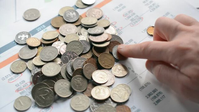 finger counts coins Russian rubles on the table. Translate: ruble, kopeck