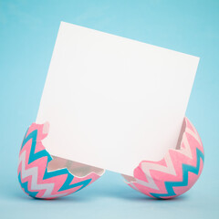 Pink and blue Easter egg cracked in half with blank greeting card for text.