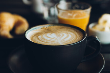 coffee with milk in black cup with drawing on the foam