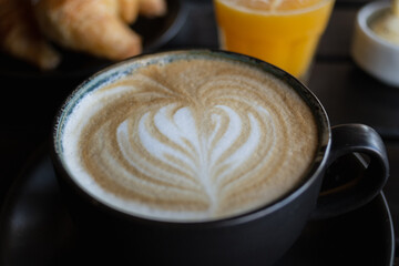 coffee with milk in black cup with drawing on the foam