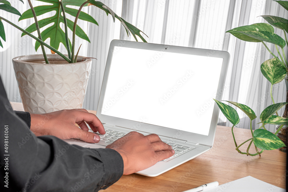 Fototapete mockup image of a man using laptop with blank screen on wooden table