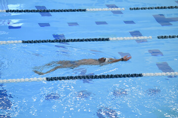 African American man swimming backstroke indoor pool - obrazy, fototapety, plakaty