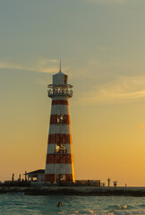 Sunset on paradise island with trees and clouds in the sky with lighthouse.