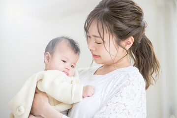 明るいリビングで赤ちゃんを抱っこしあやすお母さん　アップ