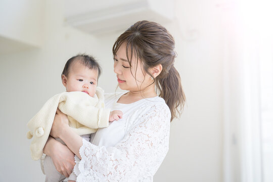 A mother holding and nursing her baby in a brightly lit living room