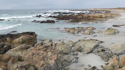 Rocky craggy pacific ocean coast, sea water waves crashing on rocks, 17-mile drive, Monterey, California USA. Gloomy nature near Point Lobos, Big Sur, Pebble beach. Dramatic cloudy rainy cold weather.