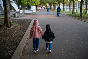 公園で手をつないで散歩する男の子と女の子 - obrazy, fototapety, plakaty