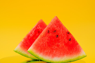  watermelon in a cut. Slices of watermelon on a bright yellow background. Appetizing summer fruits.