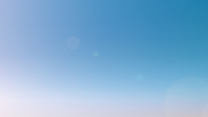 Light blue sky background with sun glare. Clean gradient light blue background. Beautiful light...