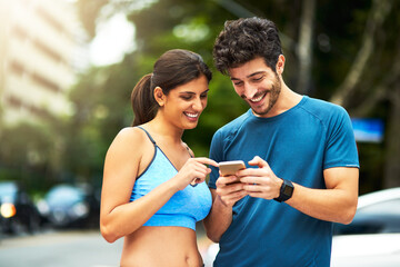 There are apps to keep track of your fitness routine. Shot of a sporty young couple using a cellphone while exercising outdoors.