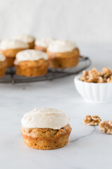 A homemade carrot cake muffin with cream cheese icing and others in behind.