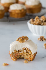 A close up of a delicious carrot cake muffin with a bite out.