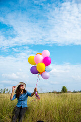 Woman holding balloons running on green meadow white cloud and blue sky with happiness Cheerful and relax. Hands holding vibrant air balloons play on birthday party happy times summer sunlight outdoor