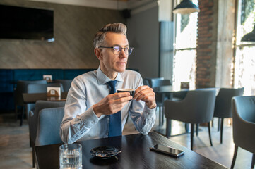 An elegant man in eyewear sitting in a cafe