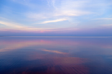 Sky background on sunset, colorful clouds. Nature abstract composition with reflections on sea water. Nature environment.