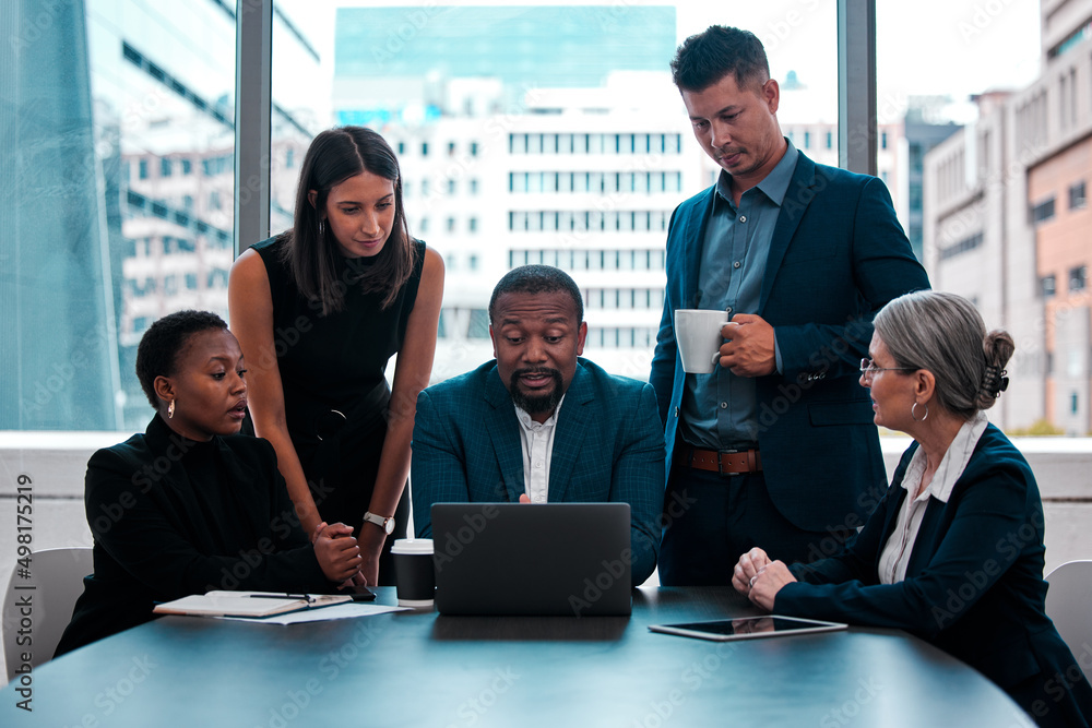 Sticker I need you all to see this presentation. Shot of a team of businesspeople gathered around a laptop in an office.