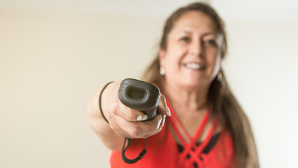 Fototapeta premium Latin mature woman playing with wireless controller