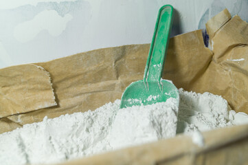 White filler in an open paper bag. Finishing dry mixture for leveling walls and ceilings. Repair in the house with your own hands. DIY. Selective focus