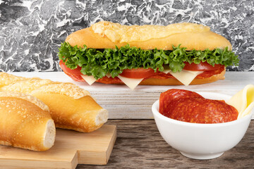 Delicious baguette stuffed with salami, tomato, cheese and lettuce. Selective focus.