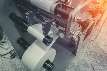 Roller of white printing paper for self-adhesive label on the shaft of the die-cutting machine in...
