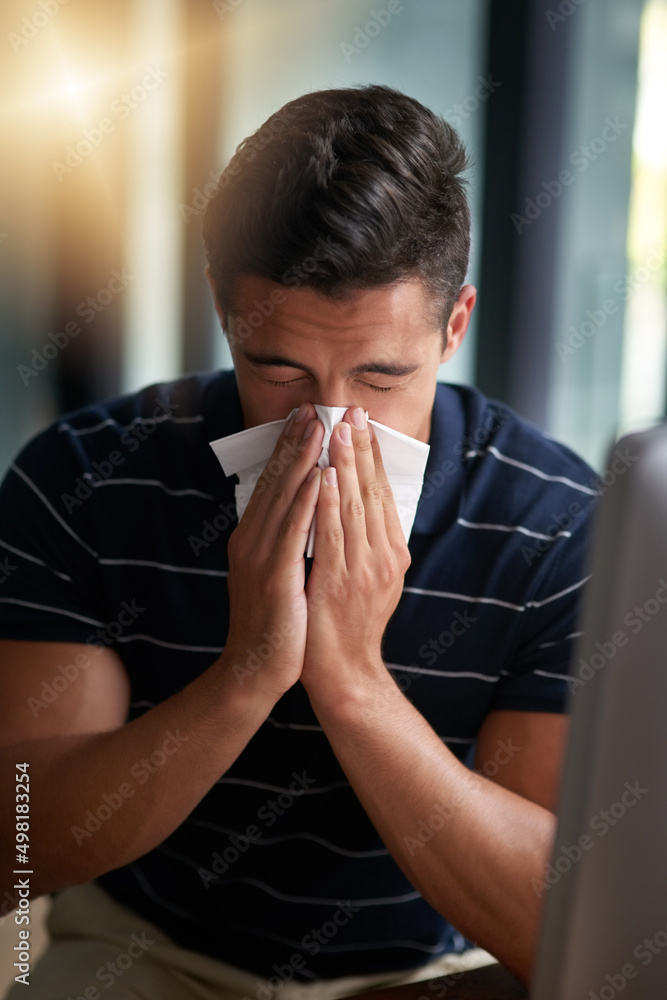 Poster The flu germs have come. Shot of a young businessman blowing his nose in an office.