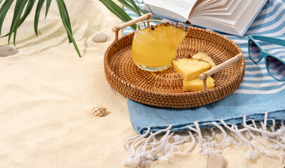 Cold pineapple cocktails on a wicker tray on beach with white sand. Summer sea vacation and travel concept. Exotic summer drinks.