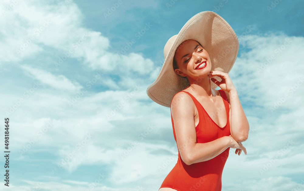 Wall mural Beautiful woman in a red swimsuit over a sky background