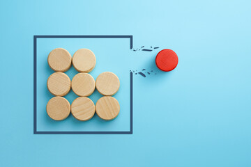 Concept of overcoming barriers, goal, target. Red wooden cube breaking through obstacle on blue background