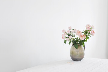 bouquet of peony roses in ceramic jug on white background
