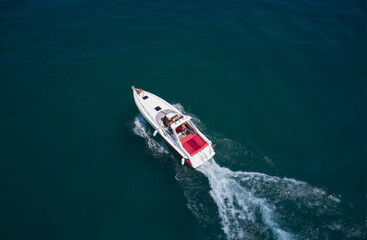 People rest on a boat. Drone view of a moving white boat on the water. Speedboat moves fast on the water top view. Speed boat with red seats aerial view.