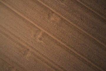 Aerial drone view of freshly plowed field ready for seeding and planting in spring. Plowed field in Italy, drone view. Background of brown earth at high altitude aerial view.