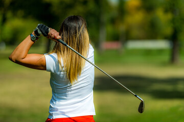 Woman playing golf, swing, rear view