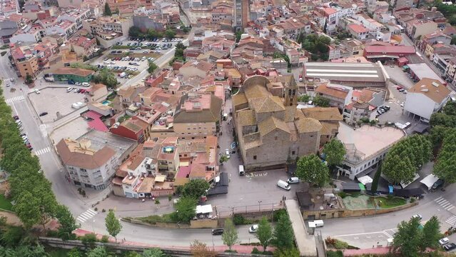 Aerial view of Tordera cityscape with terracotta tiled roofs of residential buildings and parish church 
