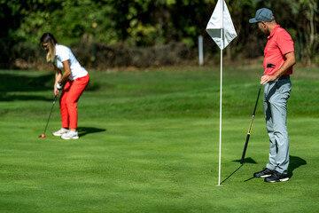 A woman and a man playing golf, woman putting