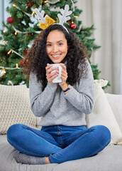 Keeping cozy at home. Shot of a young woman drinking coffee during Christmas time at home.