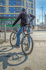 Fototapeta premium A man with a bicycle is waiting for a traffic light permit sign on a spring afternoon
