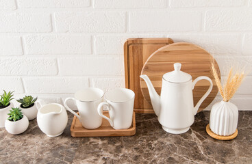 Fototapeta na wymiar coffee set of dishes on a marble countertop against the background of a kitchen board and a white brick wall. ecologically clean kitchen..