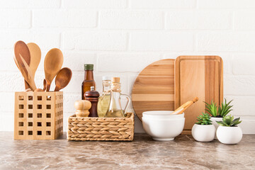 a set of various modern kitchen utensils on a marble countertop against a white brick wall....