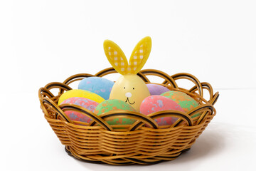 Fototapeta na wymiar Easter eggs in a wicker basket with a cute rabbit. Creative ideas for decorating eggs with an Easter bunny. Easter background.