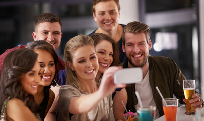 We dont need an excuse for a selfie. Shot of a happy group of friends taking a selfie while having drinks at a bar together.